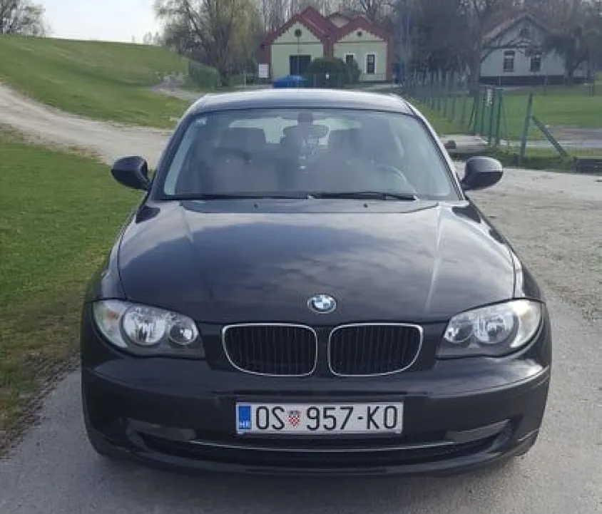 A black BMW 1 Series parked on a gravel road.