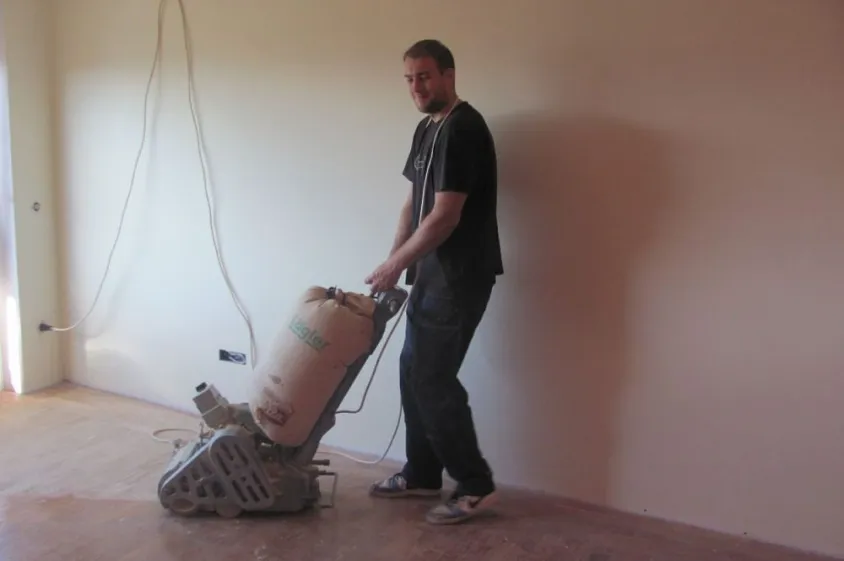 Sanding hardwood floors with a floor sander.